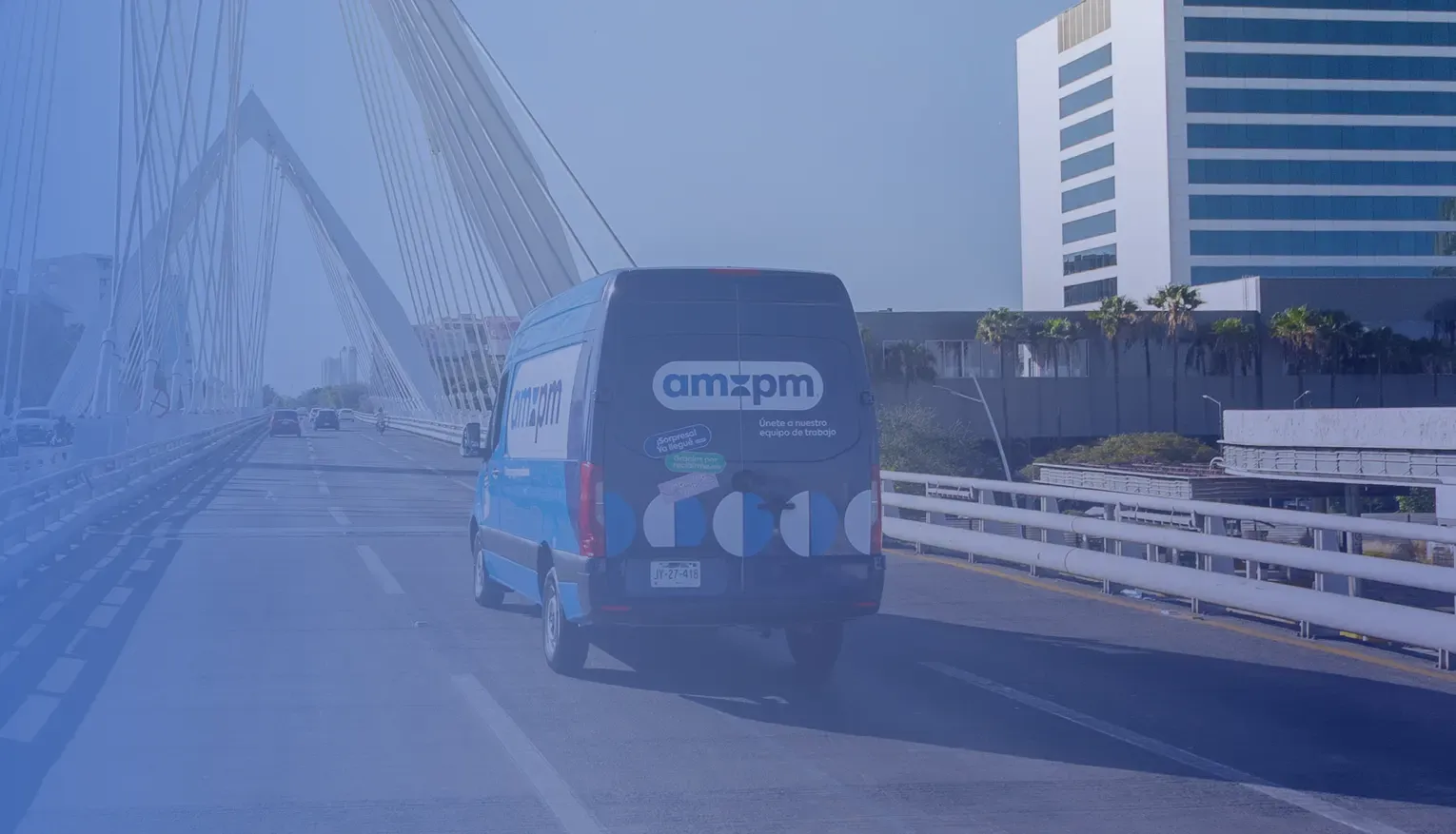 ampm delivery van driving across a cable-stayed bridge in the city