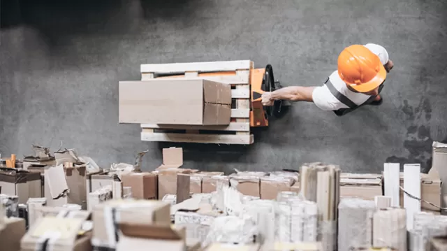 Overhead view of a worker moving a boxed pallet with a pallet jack in a warehouse