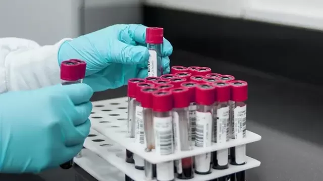 Gloved hands handling barcode-labeled blood specimen tubes in a rack