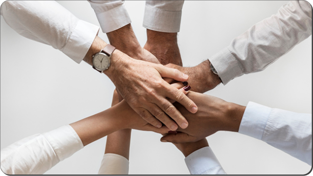 Team members stacking their hands together in a show of unity