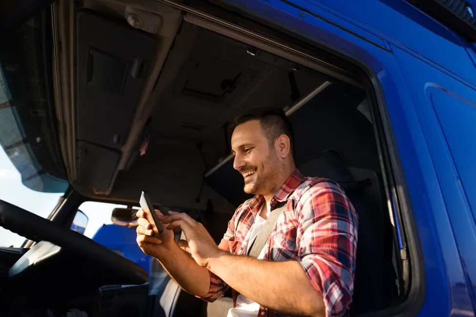 Smiling truck driver using a smartphone in his cab